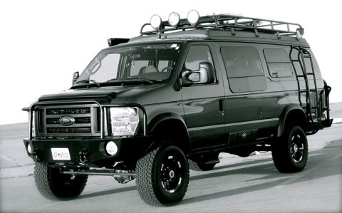 1987 Ford Bronco - Modified Ford E-Series van with off-road upgrades, including a brush guard and roof lights.