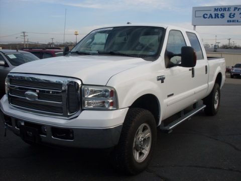 1995 Ford F-150 - A white crew cab pickup truck is parked in a lot with other vehicles and a sign in the background.