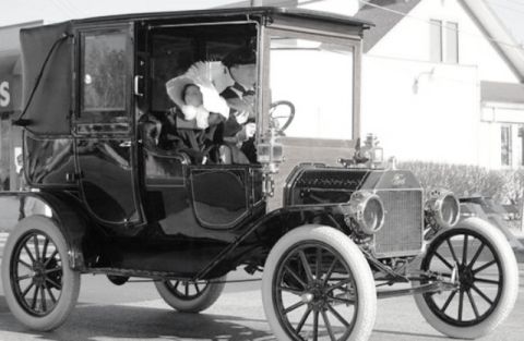 1912 Ford Model T - A 1912 Ford Model T town car is shown with passengers in the enclosed cabin.