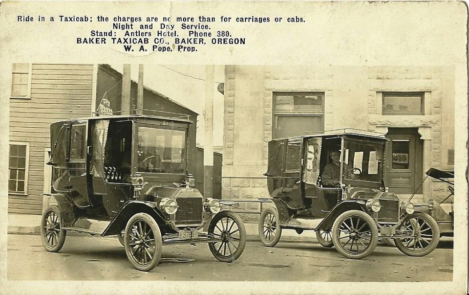 Vintage Baker Taxicab Co. postcard showing two early enclosed town-car taxis at the curb