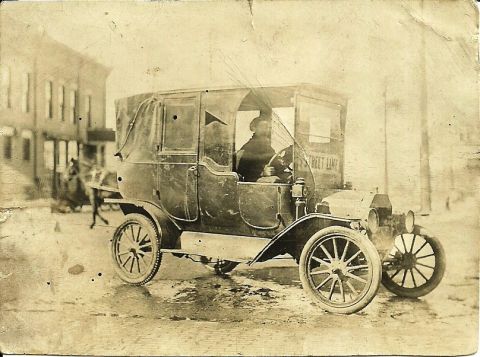 1914 Ford Model T - A vintage town car, possibly a taxi, with 'Street Line' visible on its side, navigates a wet street.