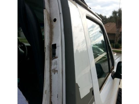 1992 Ford Bronco - The door frame of a white vehicle shows signs of wear and tear, with rust and peeling paint evident.
