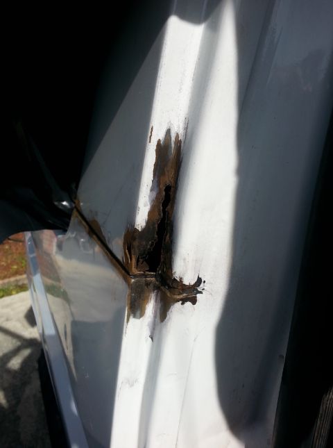 1992 Ford Bronco - Significant rust damage is visible on the door jamb of a white vehicle.