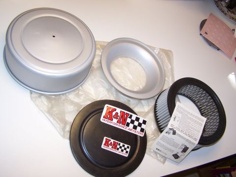 1965 Ford 427 - A K&N air filter kit is displayed, including the filter, a silver air cleaner lid, a silver air cleaner base, and two K&N stickers with ins…