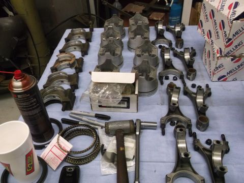 1967 Ford Mustang - Various engine components are organized on a workbench, suggesting an engine rebuild or assembly process.