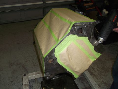 1967 Ford Mustang - An engine block is prepared for painting, covered in masking paper and secured with green tape, while a heat gun is held nearby.