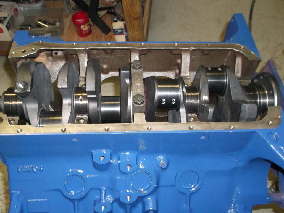 Close-up of a blue engine block with a crankshaft and connecting rods installed