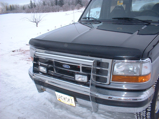 Black Ford Bronco front end with chrome grille and bumper, in snow