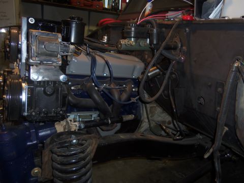 1968 Ford Bronco - Close-up view of a V8 engine, likely undergoing a steering upgrade, showing the power steering system and exhaust components.