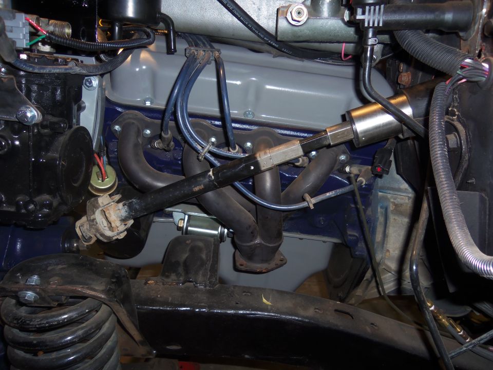 Engine bay showing exhaust manifold, spark plug wires, and part of the steering column