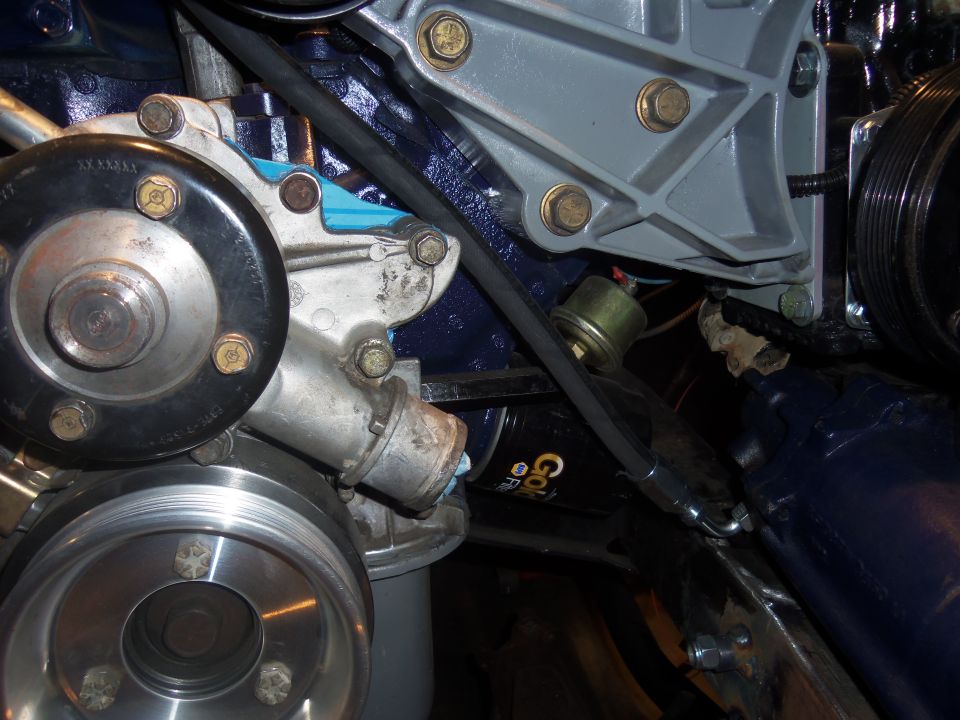 Close-up of engine parts including a water pump, pulleys, and a sensor