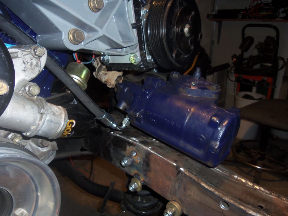 Blue steering gear box mounted on vehicle frame with engine components visible