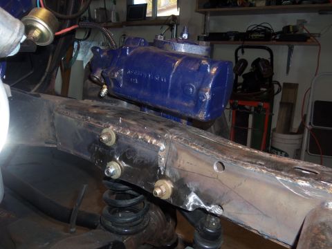 1968 Ford Bronco - Close-up view of a blue steering gearbox being installed onto a vehicle's frame, showing suspension and welding details.