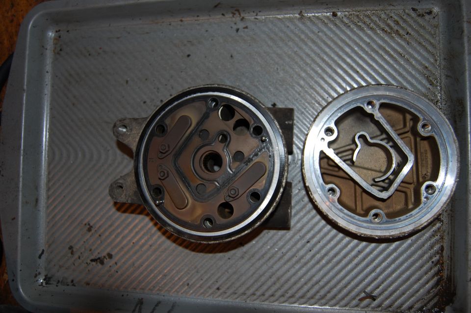 Top-down view of two disassembled round engine components with gaskets on a metal tray