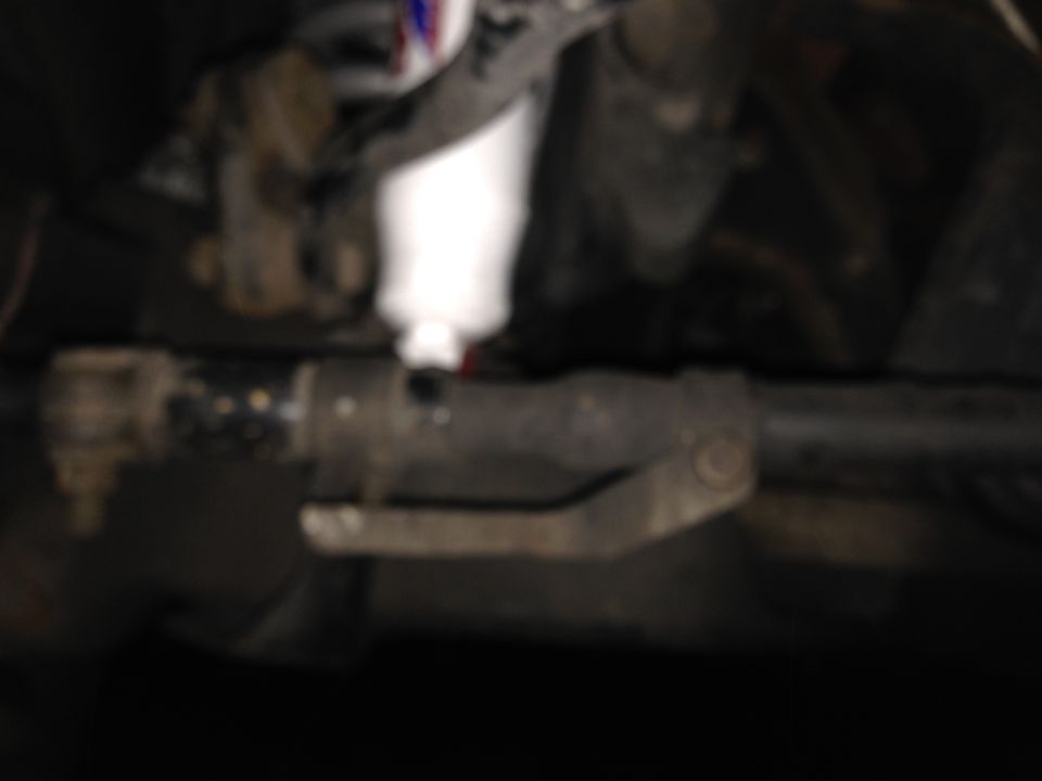 Close-up of vehicle steering linkage with a white component above