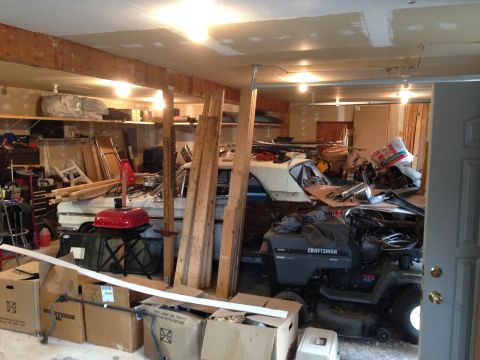1964 Ford Fairlane - A 1964 Ford Fairlane is partially visible in a messy garage, alongside a lawnmower and storage boxes.