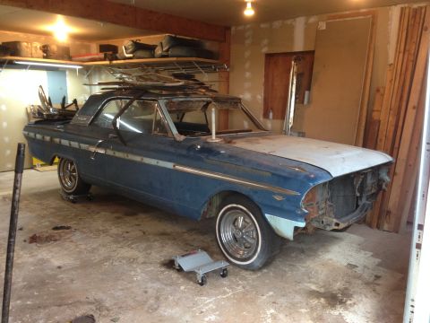 1964 Ford Fairlane - A blue 1964 Ford Fairlane coupe sits in a garage, appearing to be undergoing restoration or repair.