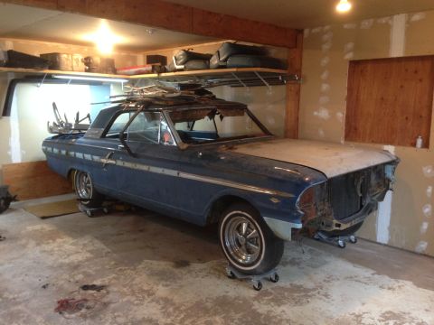 1964 Ford Fairlane - A blue 1964 Ford Fairlane sits in a garage, undergoing restoration with its front end disassembled.