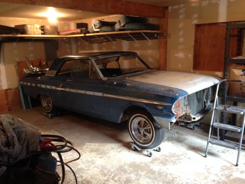 1964 Ford Fairlane - Blue 1964 Ford Fairlane coupe with chrome trim and white wall tires, parked on dollies in a garage.