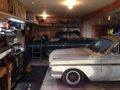 1964 Ford Fairlane - Two vintage cars, a white Ford Fairlane and a blue coupe, are parked side-by-side in a cluttered garage.