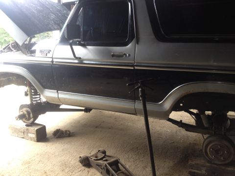 1970 Ford F-250 - This two-tone Ford Bronco is undergoing maintenance, with its hood open and wheels removed.