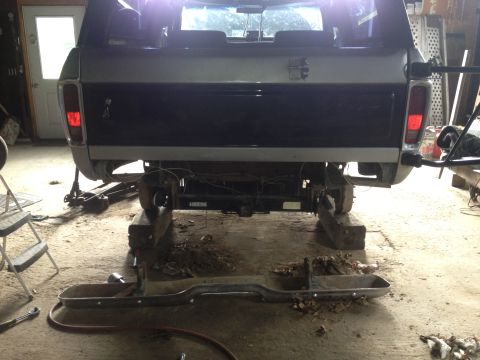 1970 Ford F-250 - Pickup truck in a garage, undergoing repairs with the rear bumper removed and the vehicle elevated on blocks.