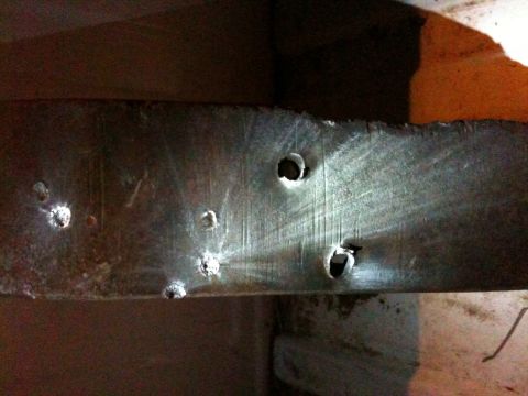 2013 Ford Mustang - Close-up of a metal beam showing multiple drilled holes and surface imperfections.