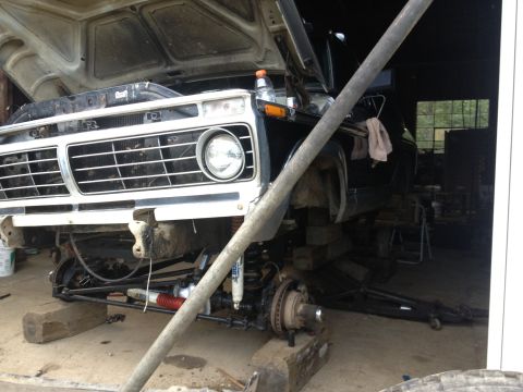 1970 Ford F-250 - Front view of a 1973 Ford F-Series truck with its hood open, being worked on in a garage.