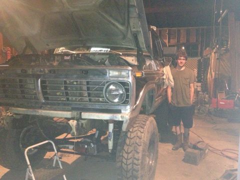 1970 Ford F-250 - A man stands beside a lifted Ford F-Series truck in a garage, with the hood open.