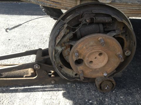 1970 Ford F-250 - Close-up of a worn and rusted rear drum brake assembly, showing the brake shoes, springs, and wheel cylinder.