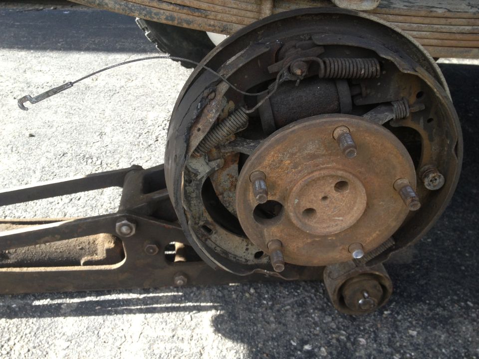 Rear drum brake assembly with rusted components and a detached brake shoe