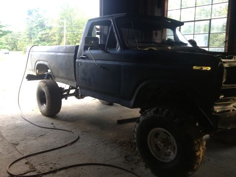 1970 Ford F-250 - This lifted Ford pickup truck is parked inside a garage, appearing to be under some sort of repair or modification.