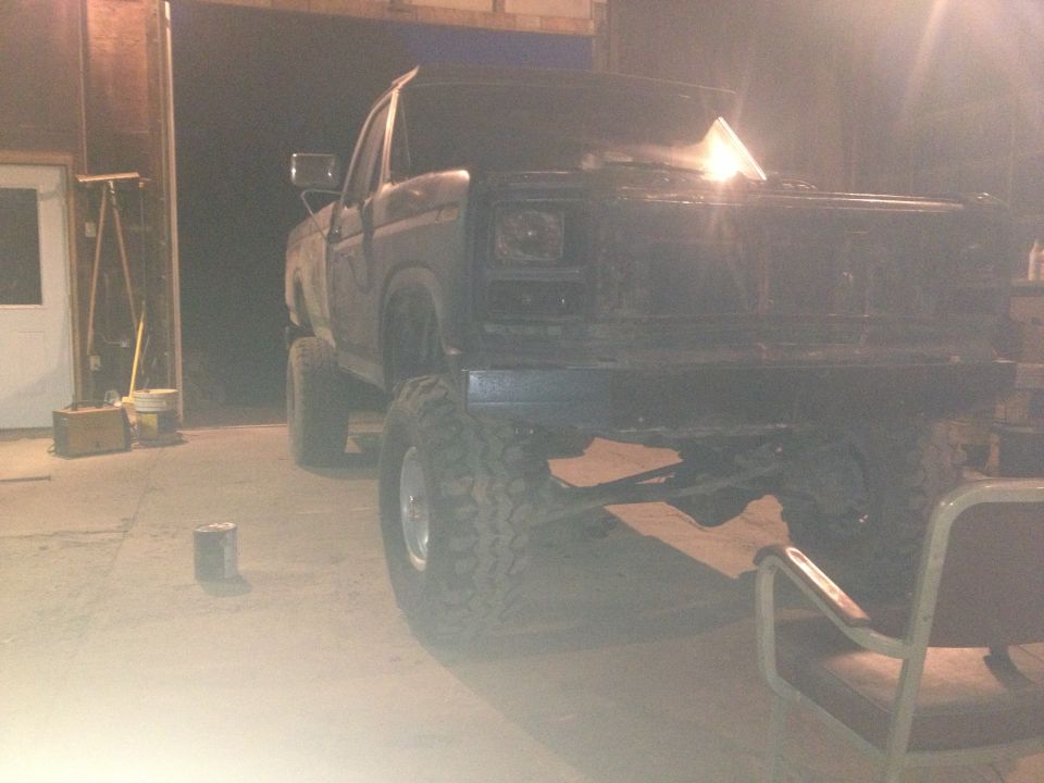 Lifted pickup truck with large tires, parked indoors