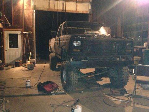 1970 Ford F-250 - Pickup truck with significant lift and off-road tires is parked inside a garage.