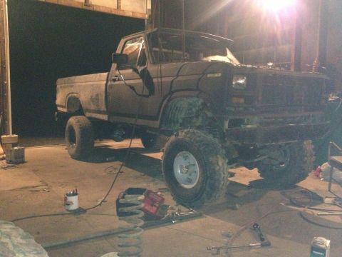 1970 Ford F-250 - A modified pickup truck is shown in a garage with its suspension components visible on the floor.