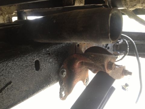 1970 Ford F-250 - A close-up view of a rusty suspension component on the underbody of a vehicle, with a large pipe visible.