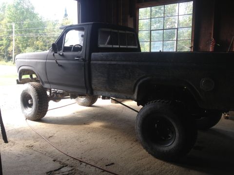 1970 Ford F-250 - This lifted pickup truck is parked inside a garage with large windows in the background.