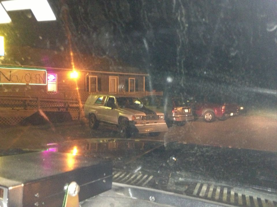 Silver SUV with black racing stripes parked at night, front bumper modified