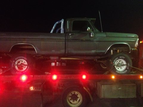 1970 Ford F-250 - A Ford pickup truck is loaded onto a flatbed trailer at night, with its side profile visible.