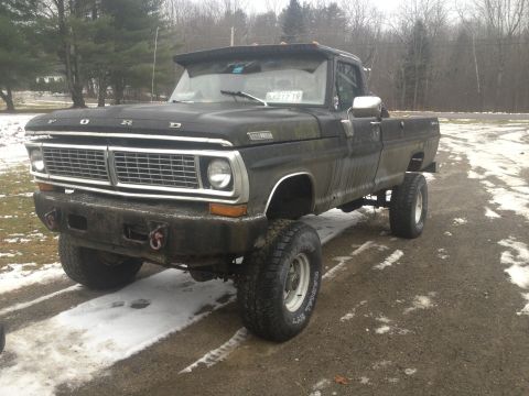 1970 Ford F-250 - This lifted black 1970 Ford F-250 pickup truck is shown in a three-quarter front view, large off-road tires.