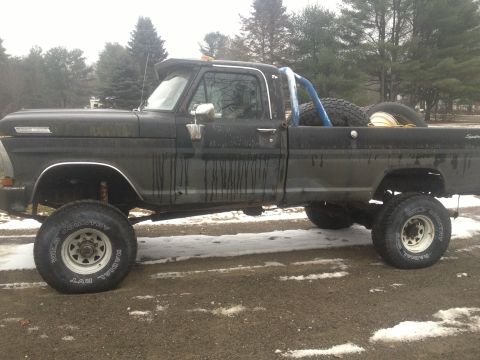 1970 Ford F-250 - Side view of a lifted 1970 Ford F-250 pickup truck with a roll bar and spare tires in the bed.