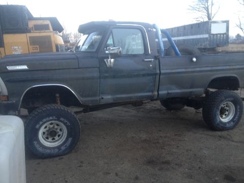 1970 Ford F-250 - This lifted 1970 Ford F-250 pickup truck features a dark green paint job and large off-road tires.