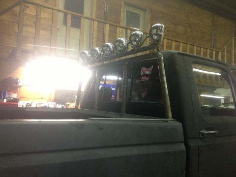 1970 Ford F-250 - A dark-colored truck is parked indoors, a custom-mounted light bar with five chrome lights above the rear window.