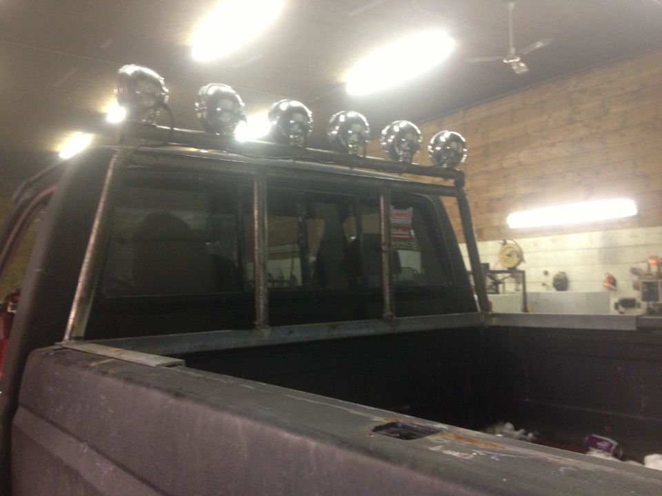Truck bed with custom metal rack holding five skull-shaped lights above the cab window