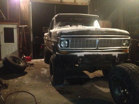 1970 Ford F-250 - Front view of a 1970 Ford F-250 truck covered in snow inside a garage.