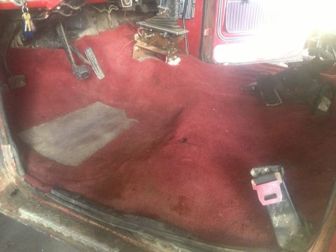 1970 Ford F-250 - Interior view of a vehicle showing red carpeting, floor shifter, and a seatbelt buckle.