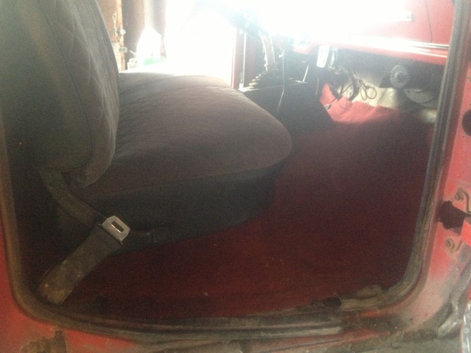 Red truck interior with dark fabric seat and red carpet floor. Seatbelt visible