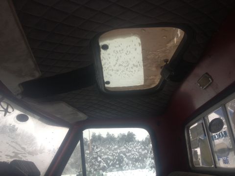 1970 Ford F-250 - The quilted headliner and sunroof are visible inside the truck cab, with a snowy view through the windows.