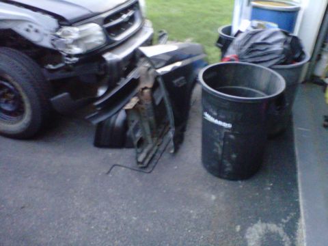 1994 Ford Bronco - The front of a black SUV shows significant damage, with parts scattered around it.