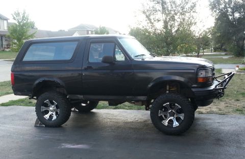 1994 Ford Bronco - Side view of a lifted 1994 Ford Bronco with custom wheels and front bumper.